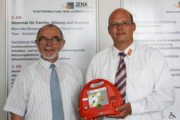 Markus Wimmer vom ASB Jena übergibt an Bürgermeister Frank Schenker einen neuen Defibrillator.