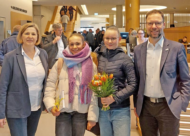 Bibliotheksleiterin Katja Müller und Oberbürgermeister Dr. Thomas Nitzsche überreichten den ersten Besucherinnen Sophia Sust und Emma Schwarze Blumen und ein Buch.