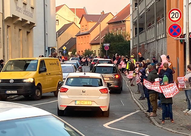 Mit einer Menschenkette entlang der Camsdorfer Straße fordern die Anwohner die Beendigung des Verkehrsversuches.