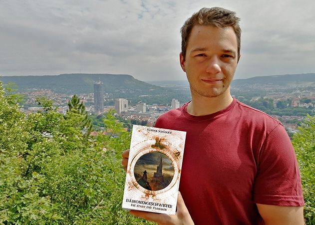 Autor Florian Schädlich mit seinem neuen Buch „Dämonengeschwister – Die Stadt der Flammen“.