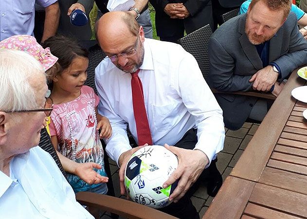 Ein kleines Mädchen aus der im Haus befindlichen Kita „Kinderzeit“ schenkte Martin Schulz spontan einen schön bemalten Fußball. Diesen möchte der SPD-Politiker seinen Kindern mit nach Hause nehmen, so Schulz. Rechts im Bild: SPD-Bundestagsdirektkandidat (Wahlkreis Jena-Sömmerda-Weimarer Land) Christoph Matschie.