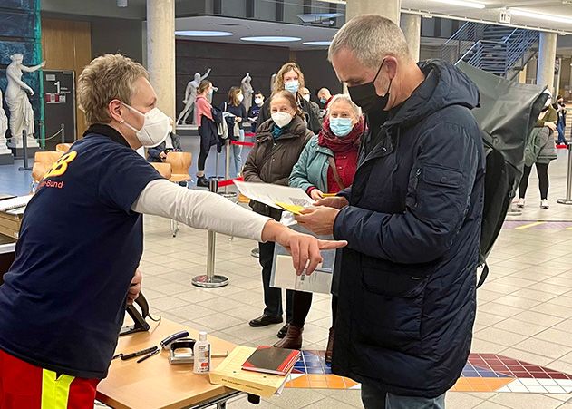 Yvonne Fischer-Zettlitzer vom ASB zeigt Herrn Büker den Weg zur seiner Booster-Impfung.