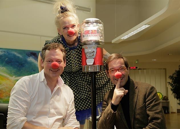 Ein weiterer humorvoller Baustein auf der Palliativstation am UKJ: Dr. Eckart von Hirschhausen übergibt Deutschlands ersten Witzeautomaten. PD Dr. Ulrich Wedding, Chefarzt der Palliativstation (rechts im Bild) und Klinik-Clown Frau Blau freuen sich.