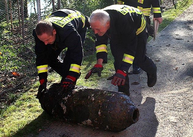 Feuerwehrleute rollen die nun ungefährliche Fliegerbombe zum Auto.