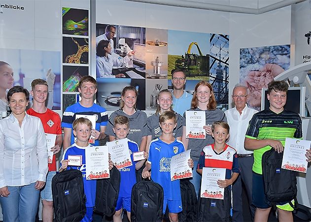 Nadine Cunäus, Personalleiterin der Carl Zeiss Jena GmbH (links), und Hartmut Beyer (2.v.r.) sowie Jörg Triller (hinten) von der Kinder- und Jugendfußballstiftung Jena gratulieren den zehn Nachwuchsfußballern.