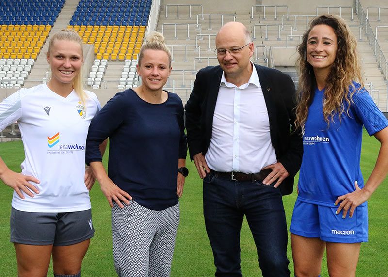 Spielerin Any Adam, FCC-Präsidiumsmitglied Laura Brosius, Jenawohnen-Chef Tobias Wolfrum und Spielerin Julia Arnold präsentieren im Ernst-Abbe-Sportfeld das neue Trikot.