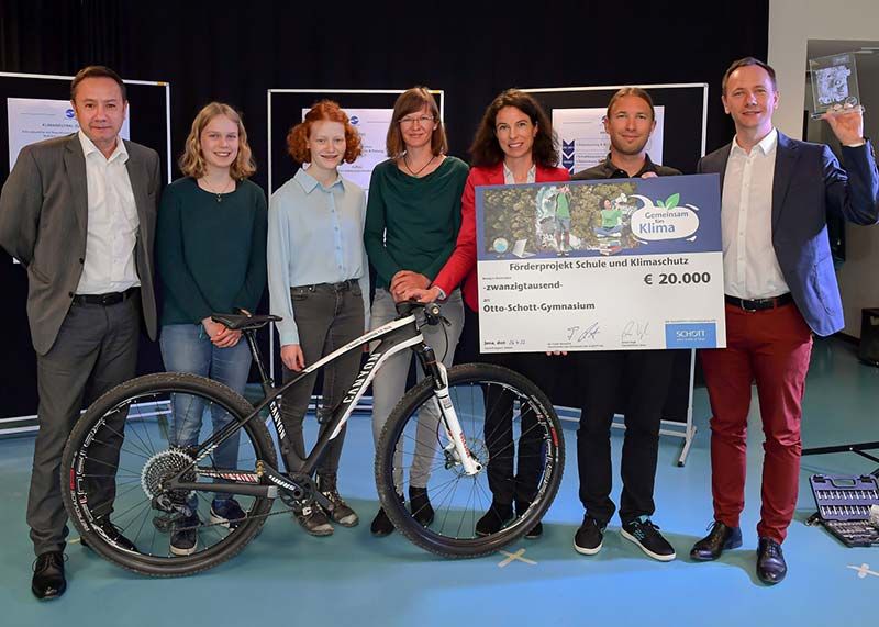 SCHOTT Standortleiter Armin Vogl (l.) übergibt den symbolischen Scheck in Höhe von 20.000 Euro an das Siegerteam des Otto-Schott-Gymnasiums und das Mitglied der Schulleitung, Christian Herrmann.