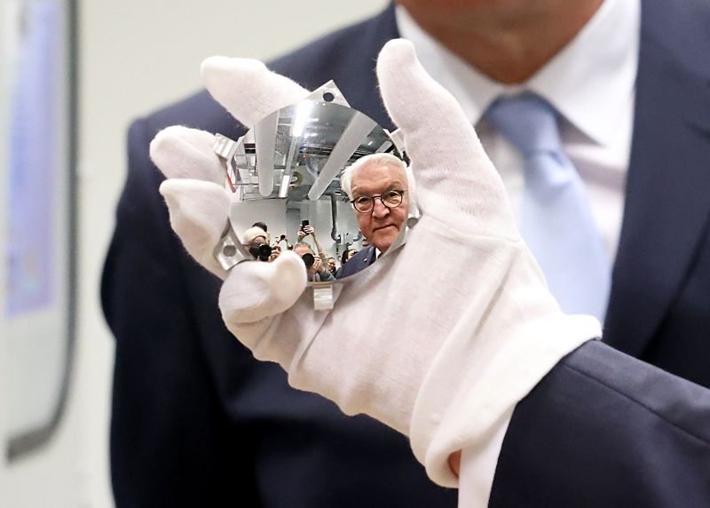 Besuch im Fraunhofer-Institut IOF: Bundespräsident Frank-Walter Steinmeier steht neben einer Präzisionsschleifmaschine von Optiken für die Anwendung im Weltraum und spiegelt sich dabei in einer der Optiken.