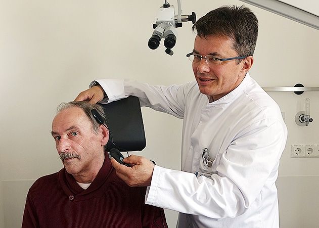 Prof. Dr. Sven Koscielny (rechts), Oberarzt der Jenaer HNO-Klinik, erklärt Klaus Fiedler (links), wie das Aufladen des vollimplantierbaren Hörgerätes funktioniert.