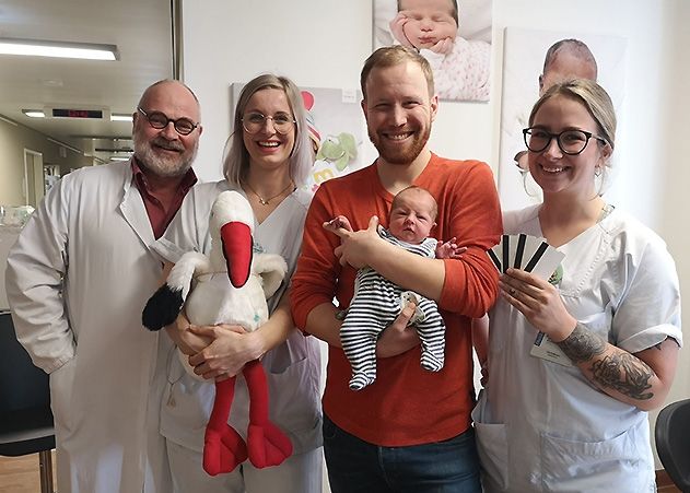 Das Team der Geburtsmedizin (v.l.: Professor Ekkehard Schleußner, Hebamme Josefine und Hebamme Lisa) freut sich, Vätern wie Christopher Kutschborski – hier mit dem kleinen Karlo – das Storchenticket anbieten zu können.