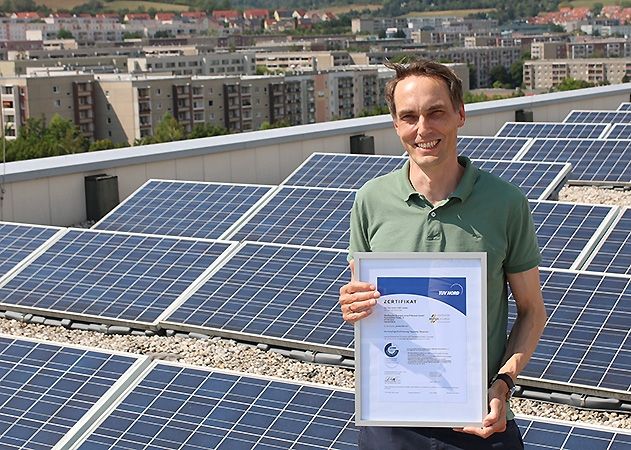Auf dem Dach des Stadtwerke-Hauses zeigt Jens Meyerrose aus dem Bereich Beschaffung der Stadtwerke Energie Jena-Pößneck das TÜV-Zertifikat. Ökostrom-Investitionen wie die in die Photovoltaikanlage in der Rudolstädter Straße machen den jenaturstrom besonders nachhaltig.