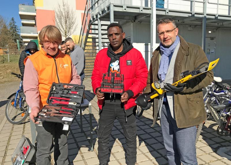 Chris Friese (ADFC), Geflüchteter aus Somalia, Gunnar Poschmann (jenawohnen), bei der Übergabe von Werkzeug an die Gemeinschaftsunterkunft am Egelsee.