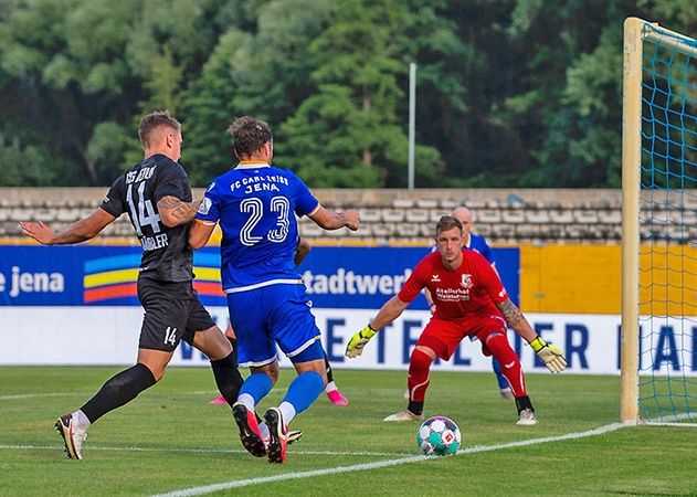 Im Zweikampf Jenas Fabian Eisele mit dem Berliner Tim Häußler. Altglienicke Torhüter Leon Bätge in Lauerstellung.